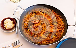 Seafood fideua with shrimps, squid and clams in paellera with allioli photo