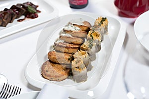 Seafood. Fish cakes and cheese rolls stuffed with fish fillet on a plate on a white background