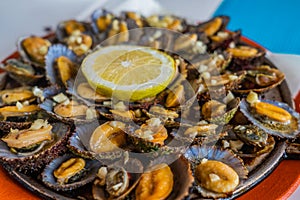 Seafood - grilled limpets served with lemon. Lapas grelhadas