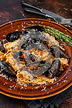 Seafood Mafaldine pasta with mussels and tomato sauce in a rustic plate. Dark background. Top view