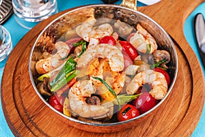 Warm salad of grilled fish pieces, shrimps and mussels in a frying pan