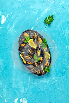 Seafood mussels with lemon and parsley in black metal plate