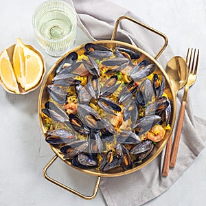 Seafood paella with mussels and shrimps in traditional plate, top view, square format