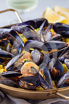 Seafood paella with mussels and shrimps in traditional plate, vertical, closeup