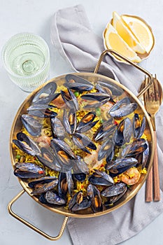 Seafood paella with mussels and shrimps in traditional plate, vertical, top view