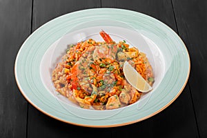 Seafood paella with rice, tomato sauce, langoustine, mussels, squid, shrimp and greens