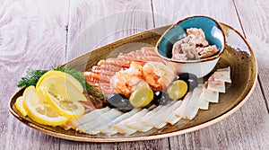 Seafood platter. Fresh cod liver, salmon, shrimp, slices fish fillet,decorated with herb on light wooden background