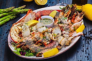 Seafood platter. Grilled lobster, shrimps, scallops, langoustines, octopus, squid on white plate