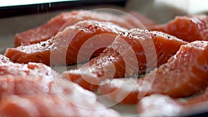 Seafood preparation - sprinkle pepper on salmon fish closeup