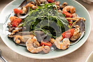 Seafood salad with shrimps and mussels with arugula on plate, close-up