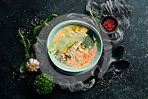 Seafood soup. Creamy tuna soup in a bowl on a black stone background. Top view. Rustic style