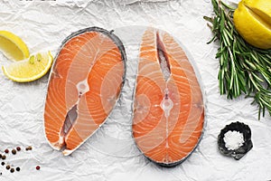 Seafood. Steaks of wild sea salmon on a light background with sea salt, rosemary and lemon. Top view.