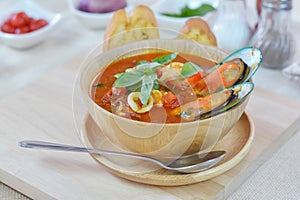 Seafood tomato soup served with garlic bread on cutting board an