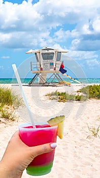 Seafront beach promenade with hand holding cocktail on sunny day in Fort Lauderdale in Florida USA