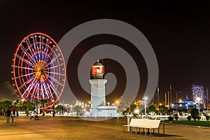 Seafront Promenade In Batumi At Night. Evening Illumination Lights In Ferris Wheel And Old Lighthouse. Seaside Park.