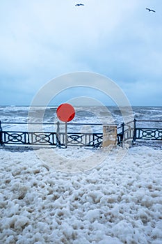 Seafront promenade in a storm, foam from the sea all over the pr