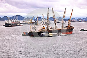 Seagoing vessels, barges, tugboats and small boats at the roadstead of Halong bay under cargo operations and underway. Port of Cam