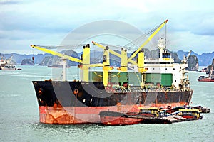 Seagoing vessels, barges, tugboats and small boats at the roadstead of Halong bay under cargo operations and underway. Port of Cam