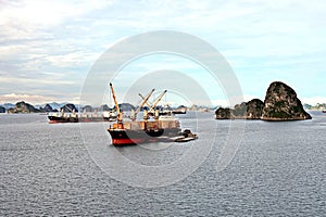 Seagoing vessels, barges, tugboats and small boats at the roadstead of Halong bay under cargo operations and underway. Port of Cam