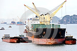 Seagoing vessels, barges, tugboats and small boats at the roadstead of Halong bay under cargo operations and underway. Port of Cam