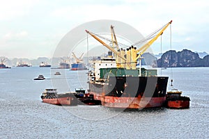 Seagoing vessels, barges, tugboats and small boats at the roadstead of Halong bay under cargo operations and underway. Port of Cam