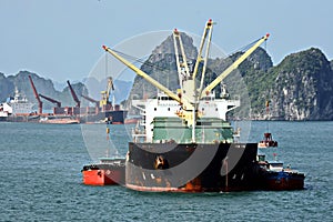 Seagoing vessels, barges, tugboats and small boats at the roadstead of Halong bay under cargo operations and underway. Port of Cam