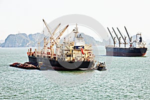 Seagoing vessels, barges, tugboats and small boats at the roadstead of Halong bay under cargo operations and underway. Port of Cam