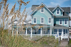 Teal coastal beach house with seagrass in the foreground photo