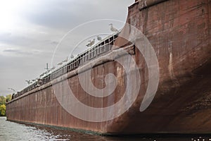 Seagulls are sitting on an old abandoned rusty ship on a gray sky background