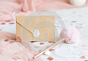 Sealed envelope near pink decorations, hearts and tulle on white table close up, mockup