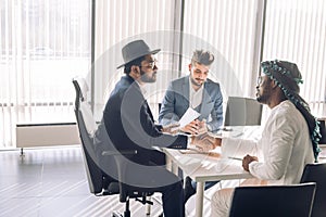 Sealing a deal. Top view of three men sitting at the desk and shaking hands