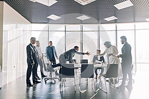 Sealing a deal. Top view of three men sitting at the desk and shaking hands