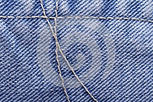 Seam yellow thread on blue jeans fabric close up. texture.