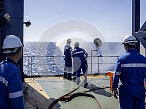 Seamen during fire emergency training drill, on board a merchant cargo ship, wearing fire fighting equipment and helmets. Rigged