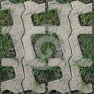 Seamles pattern of concrete road tile on the green grass path