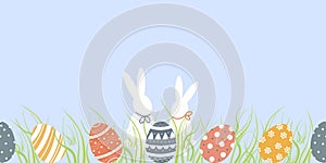 Seamless border of cute decorated Easter eggs and couple of funny bunnies in grass on blue background. Symbols of religious