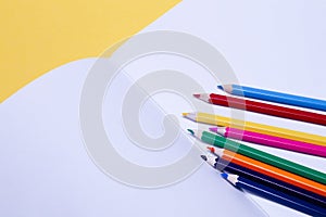 Seamless colored rainbow pencils on sheets of white paper school drawing album on yellow background isolated. Concept of free