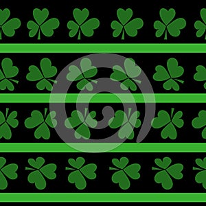 Seamless pattern of clover leaves and horizontal green stripes on a black background, a symbol of good luck and St. Patrick`s Day