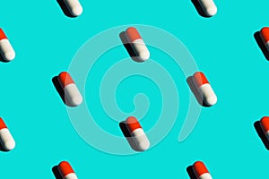 Seamless pattern diagonal rows of white and red pills in capsules with drop shadow on blue background. Healthcare