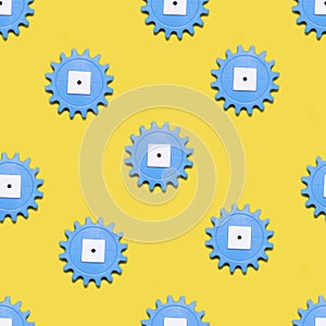 Seamless pattern with plastic gears on a yellow background. Industrial pattern. The photo
