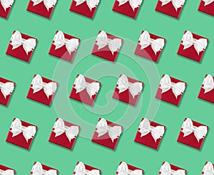 seamless pattern of red gift box with white ribbon bow on green background
