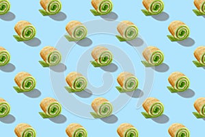 Seamless pattern of sweet rolls with green cream and soft cheese isolated on blue background.