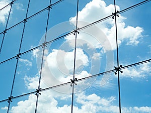 Seamless steel mesh wire on glass wall against with blue sky and white cloud outside skyscrapers building