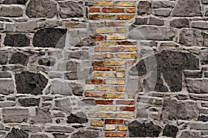Seamless texture of the old stone wall for the designer, rough gray background with an insert of red bricks