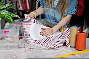 A seamstress applies a paper tailor& x27;s mold to a striped fabric.