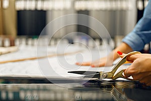 Seamstress cuts fabric with scissors in store