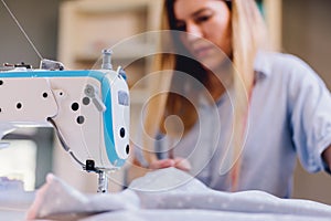 Seamstress dressmaker woman working with sewing machine in workshop