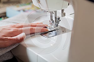 Seamstress hand guides seam on modern sewing machine