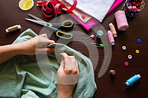 Seamstress holds a needle and thread sews clothes