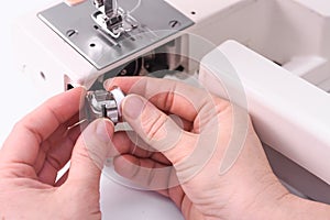 The seamstress inserts the spool into the bobbin of the sewing machine.